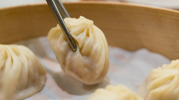 istock Chopsticks taking a pork Xiaolongbao taiwanese dumpling in a bamboo basket 955263804