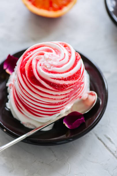 Rose water blood orange and vanilla ice-cream served on a plate. White stone background.