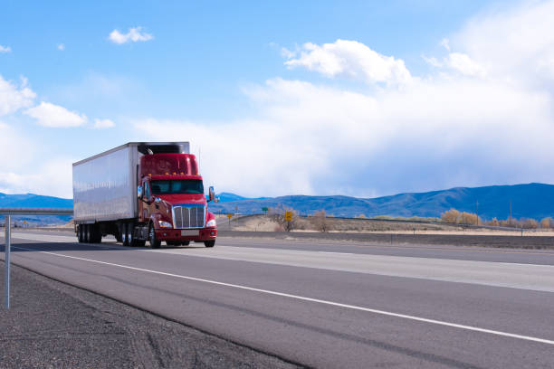 istock Big rig red semi truck with refrigerated semi trailer transporting commercial cargo on flat road in Utah 955268548