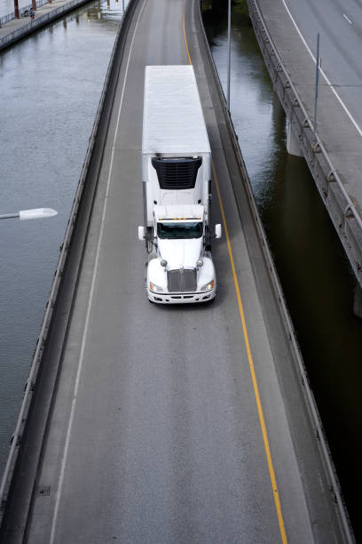 istock Big rig semi truck with refrigerator semi trailer going on the river overpass devided road 955268626