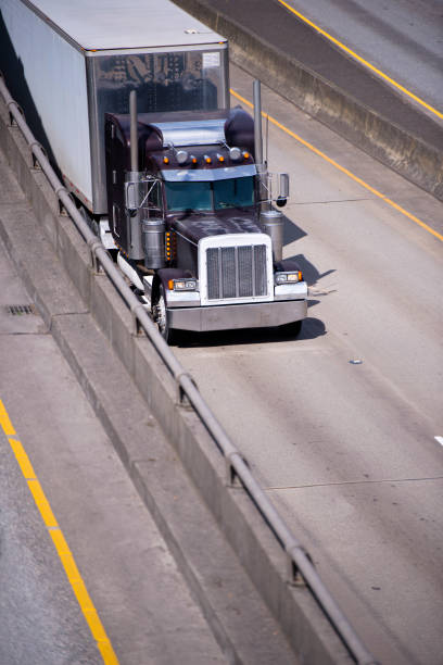 istock Dark old classic big rig semi truck with chrome accessories transporting cargo at dry van semi trailer on divided multiline highway 955268876