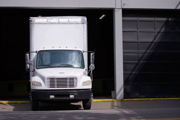 istock Middle class semi truck with box trailer for moving services standing in warehouse dock waiting for customers 955268932