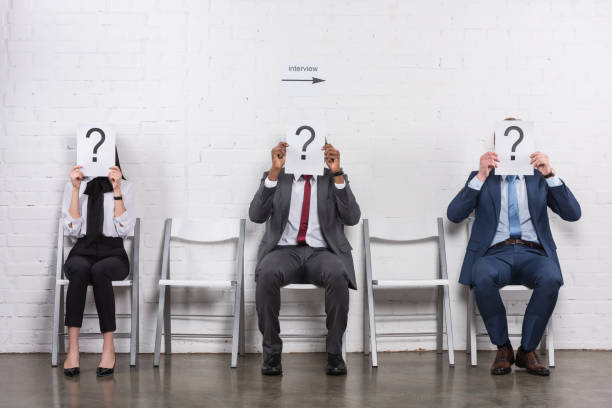 istock obscured view of multicultural business people holding cards with question marks while waiting for job interview 955269038