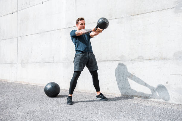 Man exercising with a kettlebell outdoors Man exercising with a kettlebell outdoors kettlebell stock pictures, royalty-free photos & images