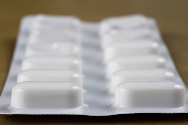 Pills in a wrapper on a wooden table. A medicine for a cold and a headache in a plastic package. Light background.