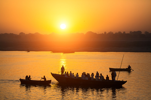 Silhouettes of boats with pilgrims during sunset on holy Ganges river, Varanasi, India.