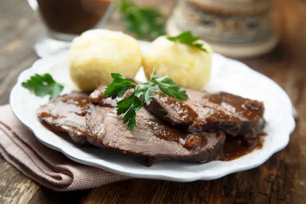 Baked meat or Sauerbraten with spicy sauce and potato dumplings