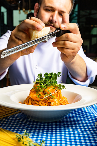 Chef Styling Plate of Spaghetti With Seafood and Microgreens