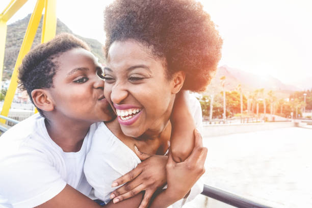 счастливая молодая мат�ь весело провести время со своим ребенком в летний солнечный день - сын целует свою маму на открытом воздухе с задней  - africa south africa child african culture стоковые фото и изображения