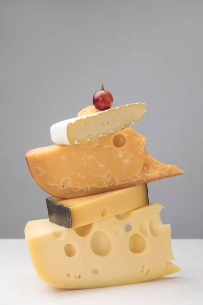 istock Grape on top of stack of different types of cheese on gray 955376086