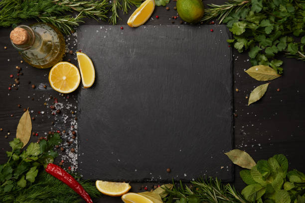 istock Black slate board with fresh herbs and lemon slices with olive oil 955388142