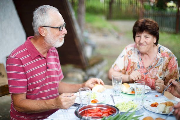 istock Senior couple having lunch outdoors with friends 955407484