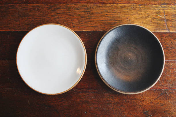 opróżnij dwa talerze (naczynie i miskę). ustawienie stołu dla dwóch osób na drewnianym stole - white pottery textured circle zdjęcia i obrazy z banku zdjęć