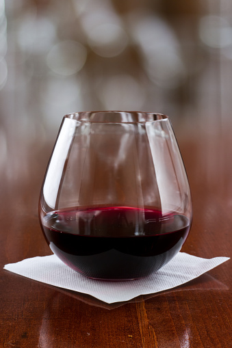 stemless glass with red wine served on a bar