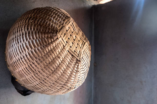 A handwoven spherical basket hanging against the corner of a shadowed interior wall.