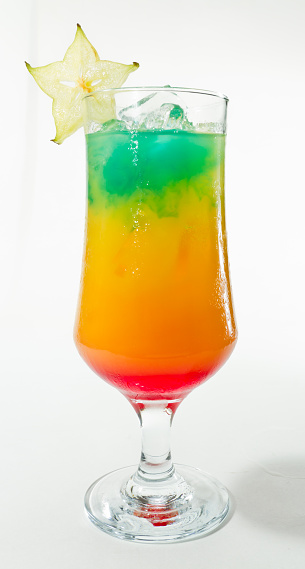 tropical drink isolated on a white background garnished with a carambola slice on the rim