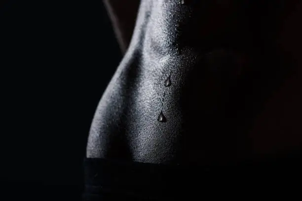 Photo of close up view of sweaty abs of sportswoman, black and white
