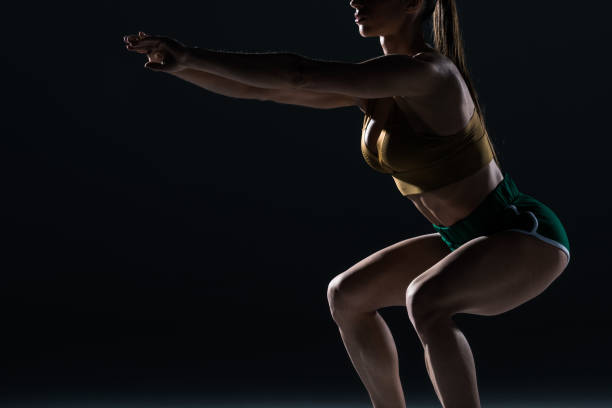 istock cropped view of muscular bodybuilder doing squats, isolated on black 955454276