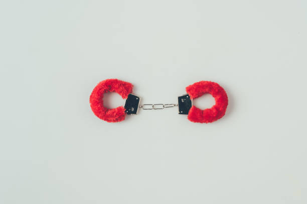 top view of locked red fluffy handcuffs isolated on white