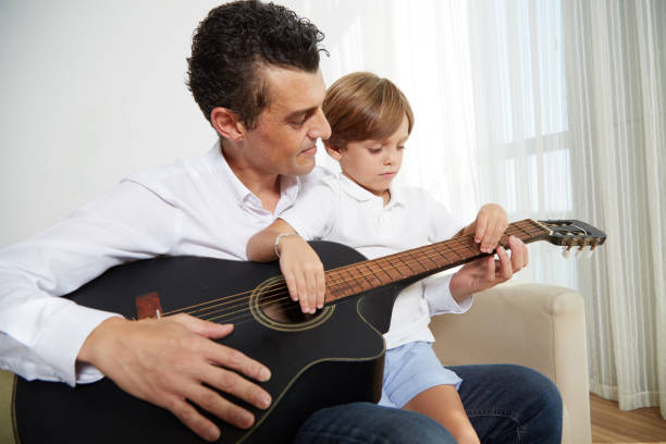 Enjoying music Father and son playing guitar together father and son guitar stock pictures, royalty-free photos & images