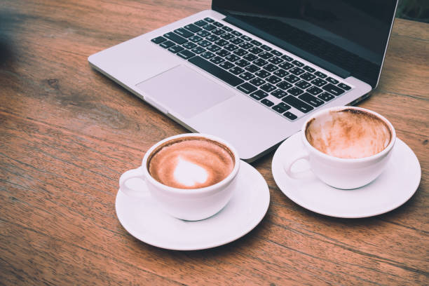 Empty cups and full coffee cup placing together with laptop on the desk