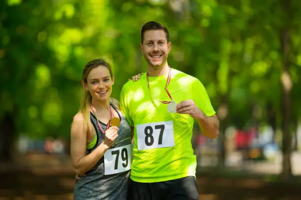 Photo of successful happy couple with medals after marathon run