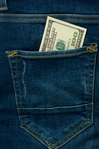 Dollars in jeans pocket. One hundred bills. Bundle of dollars closeup