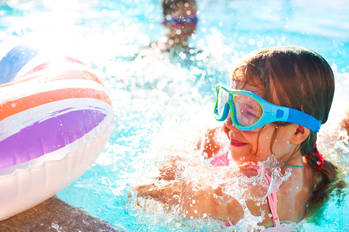 One small girl having fun in outdoor pool. Summer vacation concept