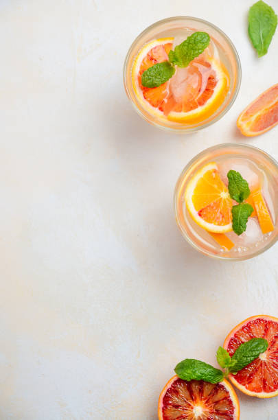 istock Cold refreshing drink with blood orange slices in a glass on a white concrete background. 955514992