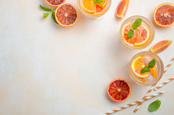 Cold refreshing drink with blood orange slices in a glass on a white concrete background. Cold refreshing drink with blood orange slices in a glass on a white concrete background. Top view, flat lay, copy space. punch bar edible stock pictures, royalty-free photos & images