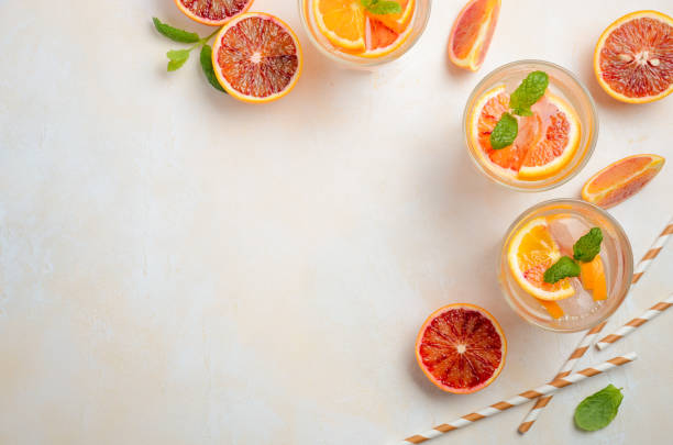 Cold refreshing drink with blood orange slices in a glass on a white concrete background. Cold refreshing drink with blood orange slices in a glass on a white concrete background. Top view, flat lay, copy space. carbonated juice stock pictures, royalty-free photos & images