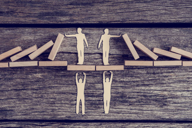 istock Cutouts of men supporting others on a bridge while they prevents domino effect 955518236