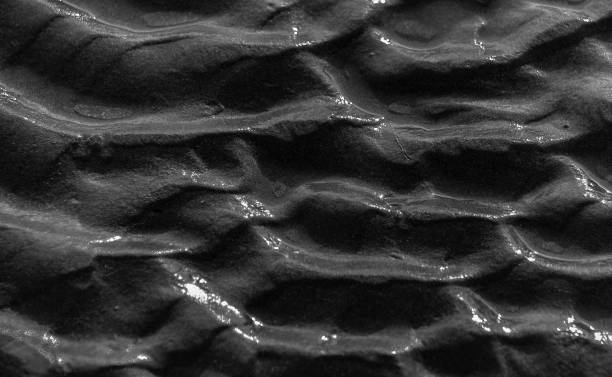 Wave patterns on sand by the beach in black and white close-up in landscape