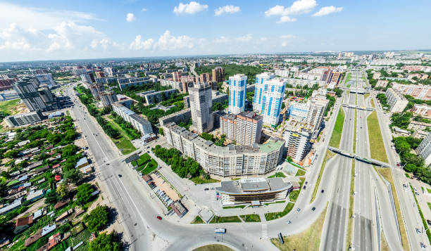 Aerial city view with crossroads and roads, houses, buildings, parks and parking lots. Sunny summer panoramic image - fotografia de stock