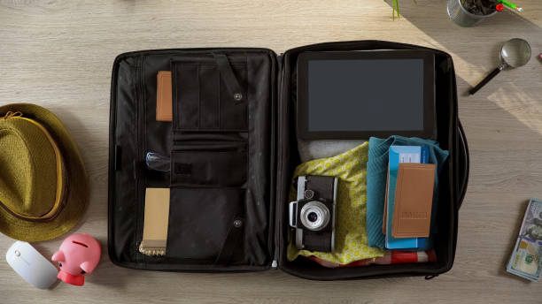 istock Documents and airplane tickets packed in suitcase, preparations for vacation 955555156