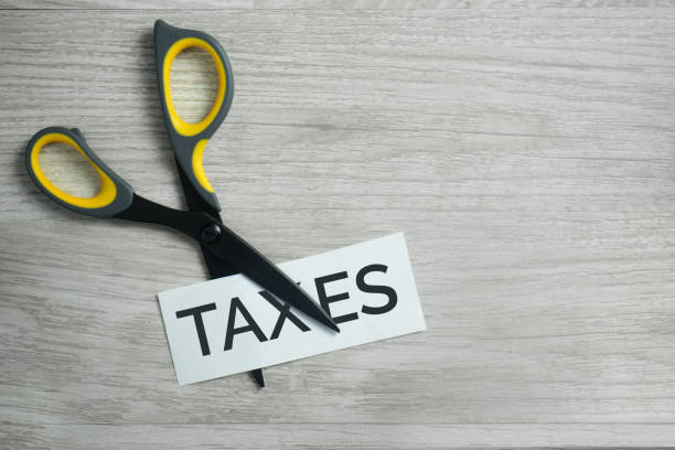Scissors cutting through a paper printed with the word taxes