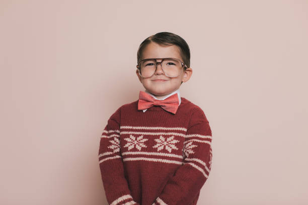 Young Christmas Sweater Boy with Cheesy Smile Young Christmas sweater boy with eyeglasses and an ugly sweater holds his hands together and makes a cheesy smile at the camera. He was a good boy this year so Santa will bring him lots of gifts and presents. He enjoys wearing his Christmas sweater and going to parties. christmas ugliness sweater nerd stock pictures, royalty-free photos & images