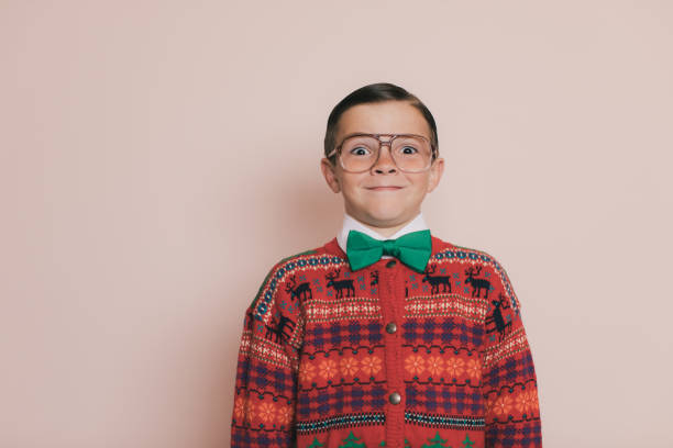 Ugly Christmas Sweater Boy with Cheesy Smile Christmas Sweater Boy with eyeglasses and an ugly sweater makes a cheesy and goofy smile at the camera. He loves giving and getting presents at Christmas. He enjoys wearing his Christmas sweater for photos. christmas ugliness sweater nerd stock pictures, royalty-free photos & images
