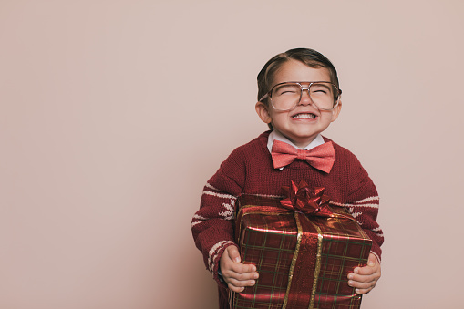 Young Christmas sweater boy with eyeglasses and an ugly sweater is laughing at the camera. He loves getting presents from Santa at Christmas. He enjoys the excitement and happiness that comes with the holidays.