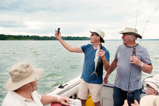 Active seniors brothers on a week-end fishing trip on the St. Lawrence River in Quebec Canada. They are happy to be together. We feel the fraternity that unites them. They also do a lot of humor. They all wear fishing hats. They are between 65 and 80 years old.
