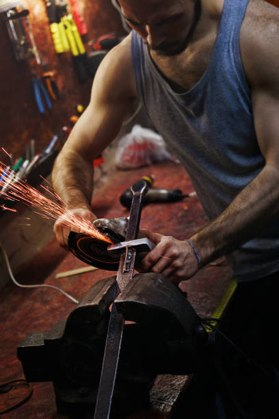 istock Blacksmith polishes crossguard of sword 955607864