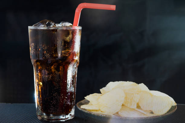 istock Glass of Cola with Potato Chips on Black Background 955615776