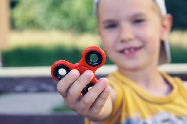 istock Young boy play with fidget spinner stress relieving toy 955629060
