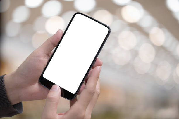 istock Male hand holding smartphone at office. Blank screen mobile phone for graphic display montage 955640748
