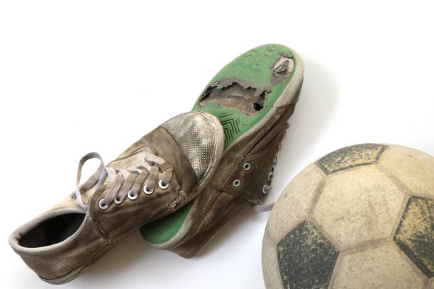 fútbol antiguo y zapatos viejos aislados sobre fondo blanco - pauper fotografías e imágenes de stock