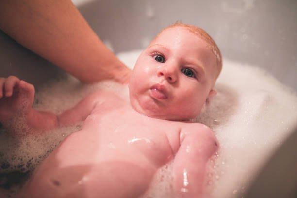 istock Happy laughing baby taking a bath playing with foam bubbles. 955654372