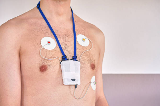 man wearing 24 hrs electrocardiogram monitor device on his chest - pulse trace computer monitor eeg equipment imagens e fotografias de stock