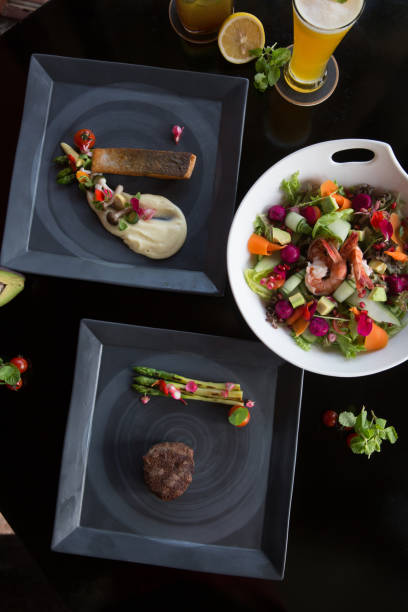 Various different tasty dishes plates on dark background. Fish, steak, salad
