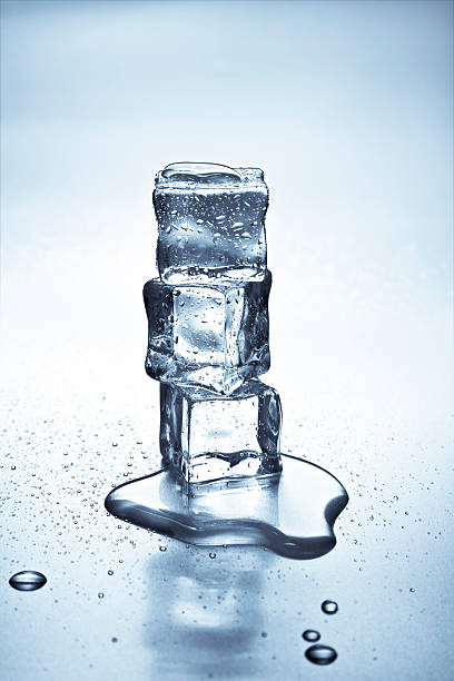 Close up of ice cubes melting and creating a puddle stock photo