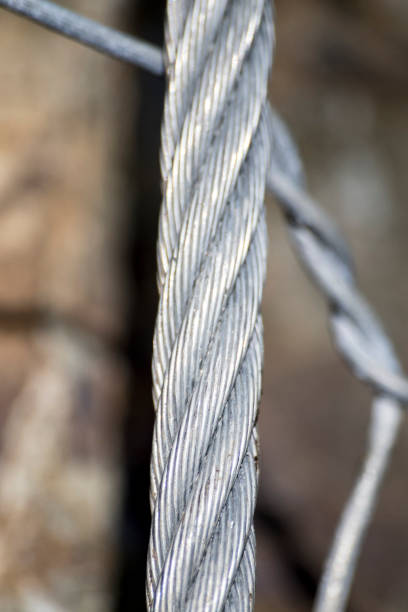 istock Strong grey steel cable with rock in the background cmposition 955665758